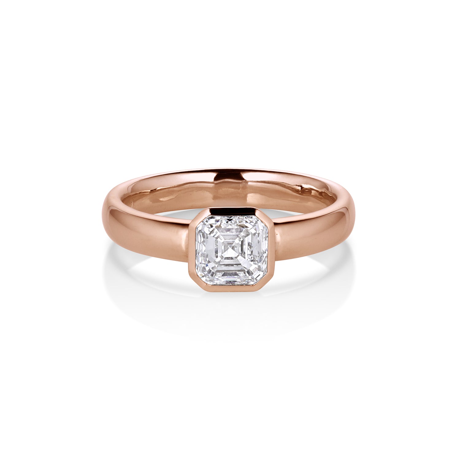 14k Rose gold mid weight comfort shaped band with Asscher cut white brilliant solitaire diamond bezel set. Shown on white background.