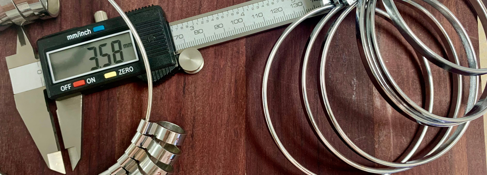 Caliper measuring a metal coil on a wooden surface