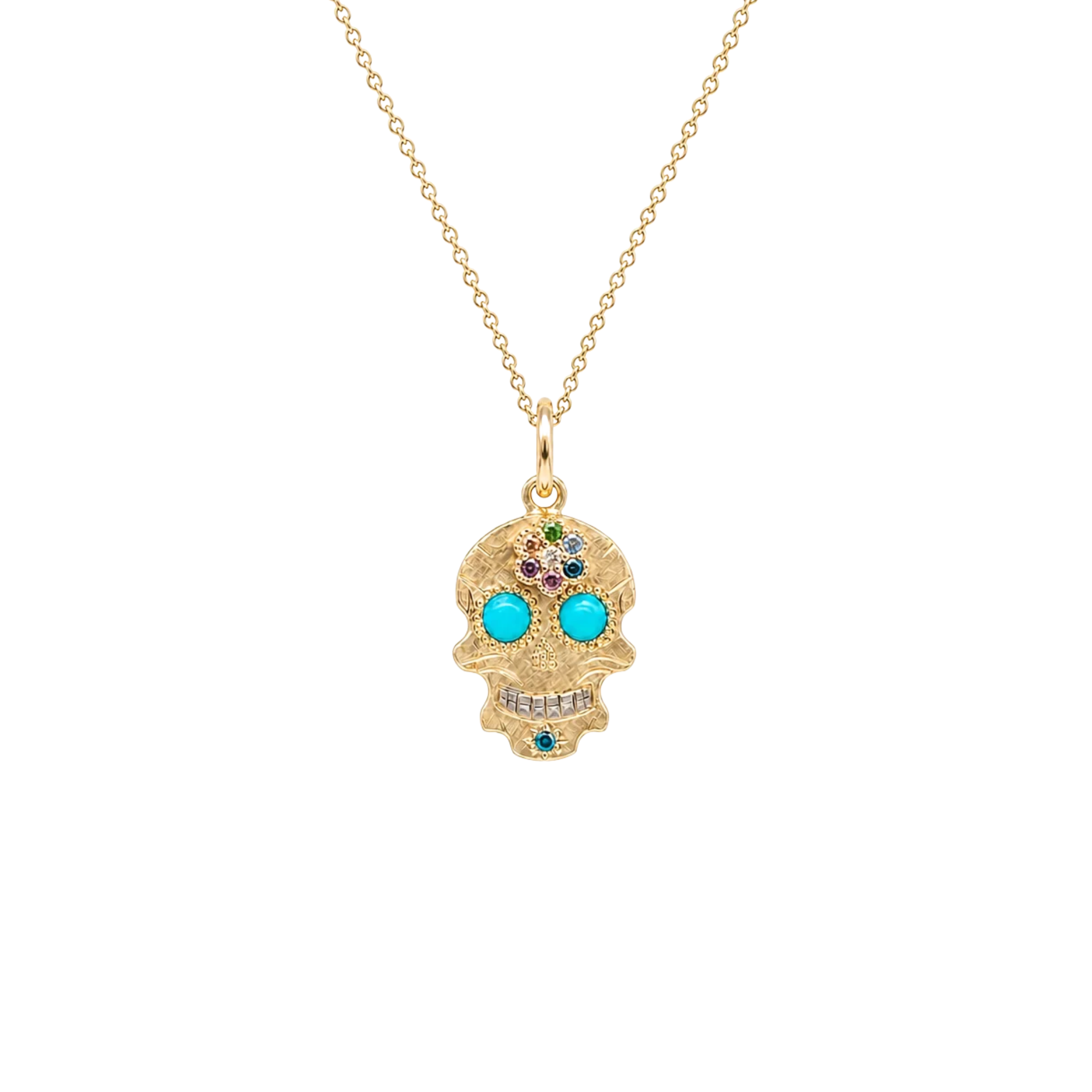 A gold sugar skull pendant necklace on a delicate gold chain, featuring turquoise-colored gemstone eyes and small multicolor rhinestones on the forehead, set against a plain white background.