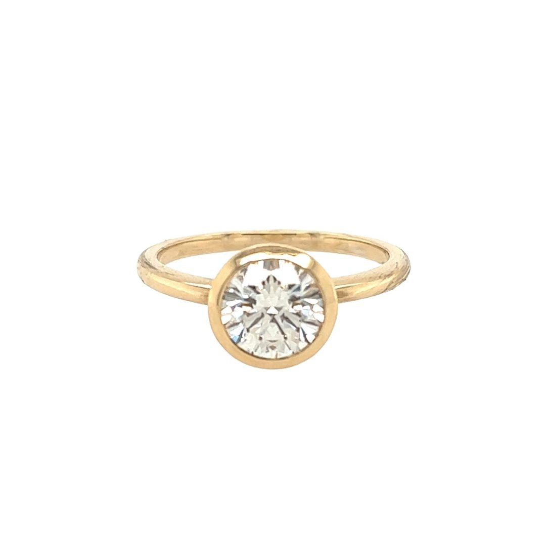 14k yellow gold ring with a bezel set diamond on a white background