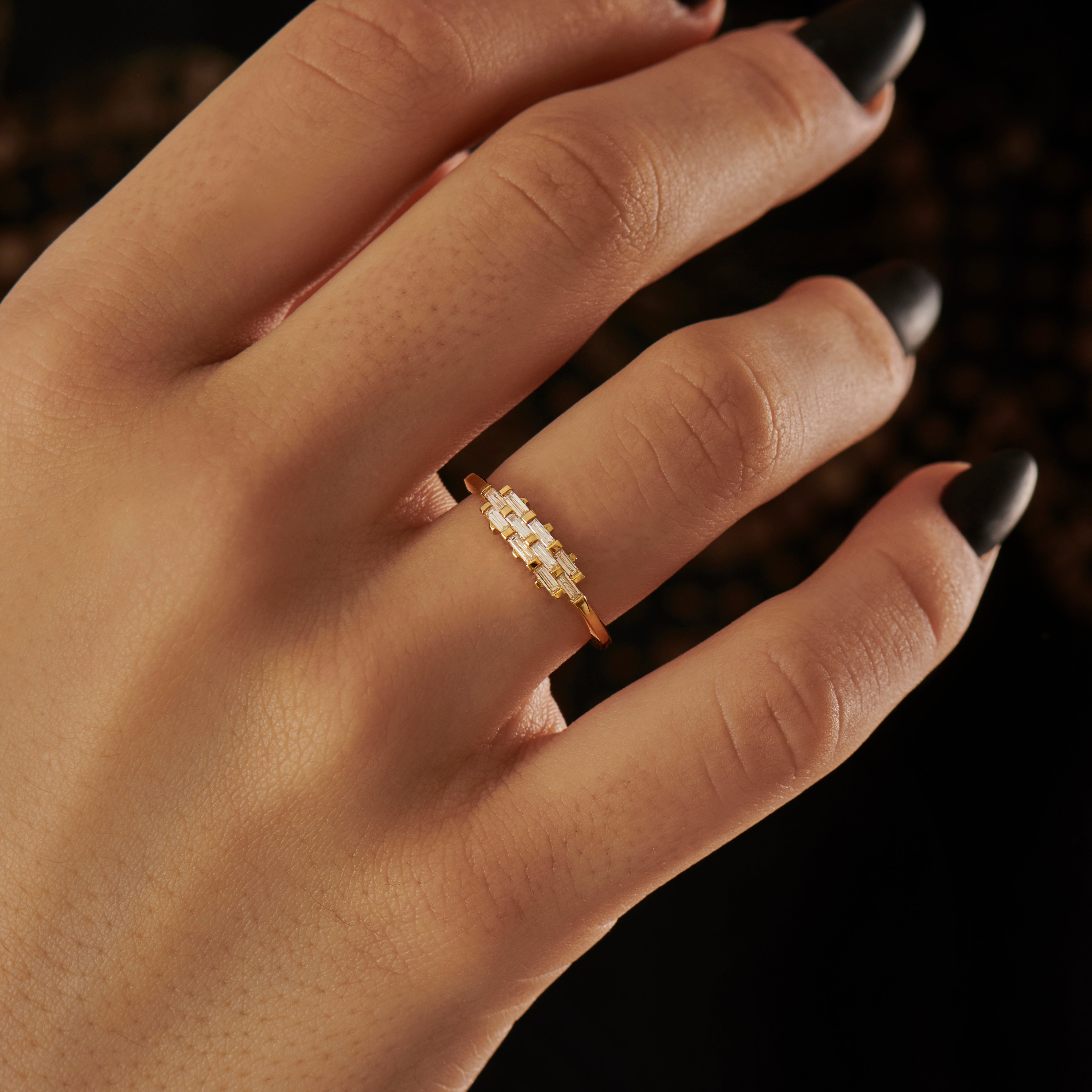 Artemer 18k yellow gold woven baguette diamond ring on model with dark background