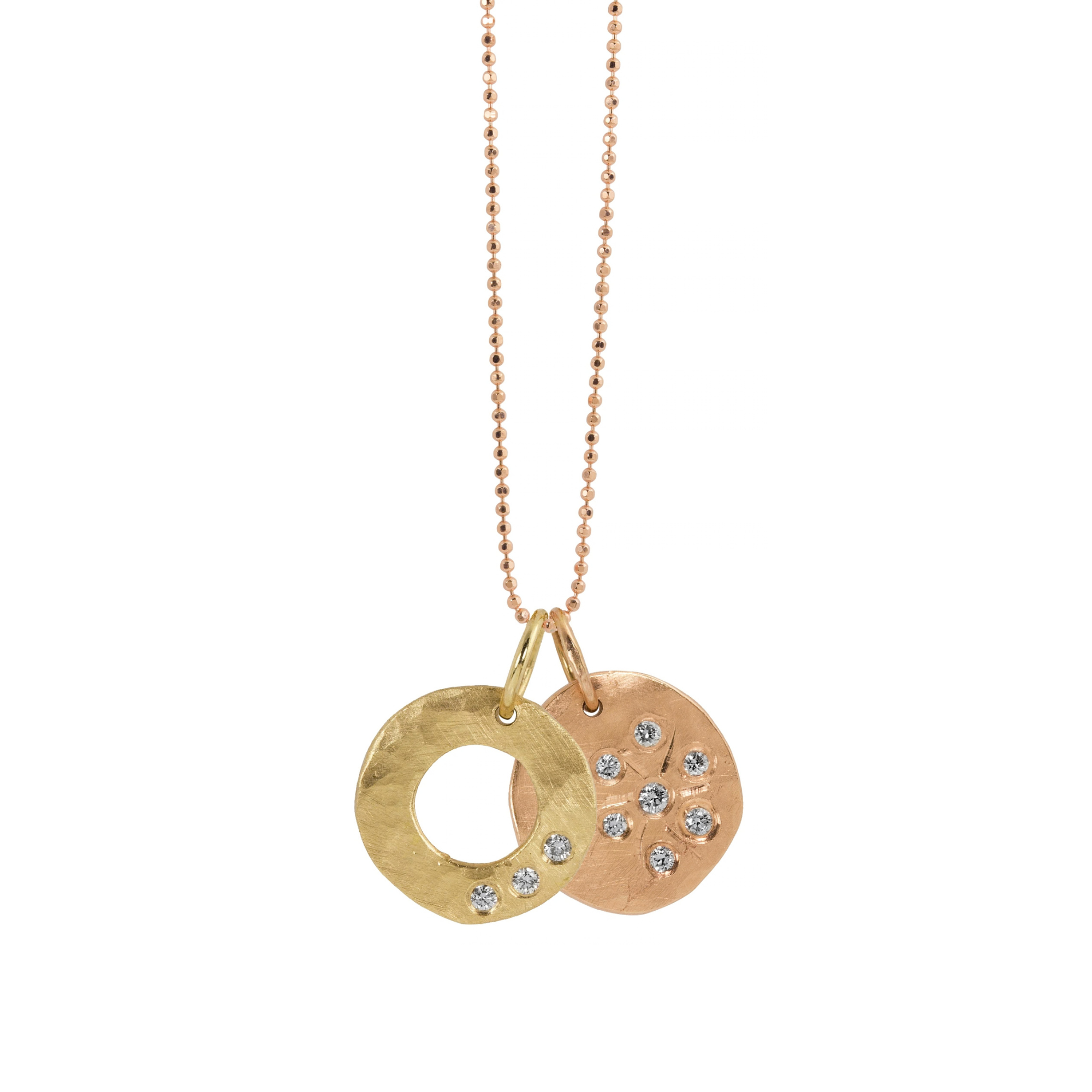14k gold open circle pendant with hammered finish and three white diamonds paired with round hammered pendant with etched starburst and white diamonds on a white background
