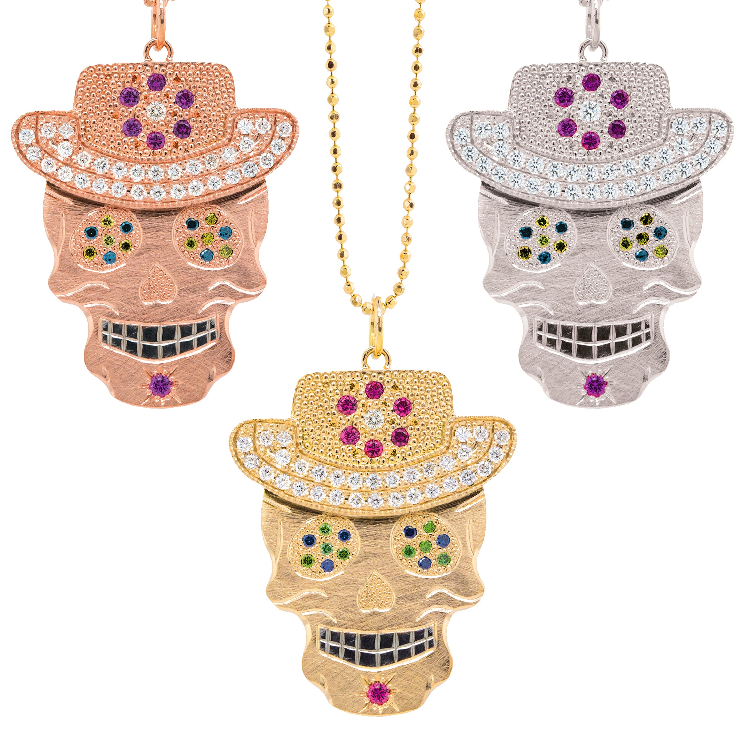 Grouping of 3 varieties of vibrant our original Ghostrider Collection Vaquero gemstone encrusted sugar skull XL pendants. Candy skull wearing cowboy hat  rhodium darkened teeth. Shown in 14k rose,yellow and white gold mixed diamond sapphires and Tzavorite. Fine detail engraving, milgrain details. Pink sapphire floral detail and diamond encrusted brim on hat. Eyes with green Tzavorite and blue sapphire pave set gemstone eyes.  Shown on 2.0mm ball chain.