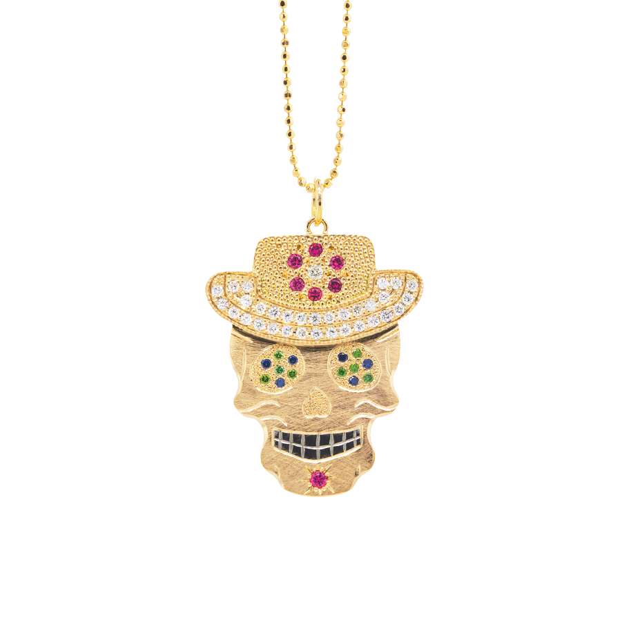 Gemstone encrusted sugar skull wearing cowboy hat yellow gold black rhodium darkened teeth. Extra large pendant in 14k solid yellow gold mixed diamond sapphires and Tzavorite. Fine detail engraving highlights features. Hat of flower clustered jewels in mixed colors. Eyes with green Tzavorite and blue sapphire pave set gemstone eyes. Large pink sapphire Flower pave set detail on hat.  Shown on 2.0mm ball chain.