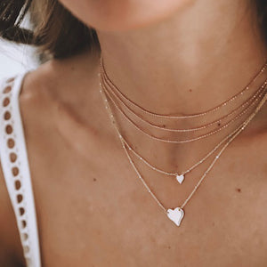 14k gold LAZA heart necklace on model with LAXA necklace