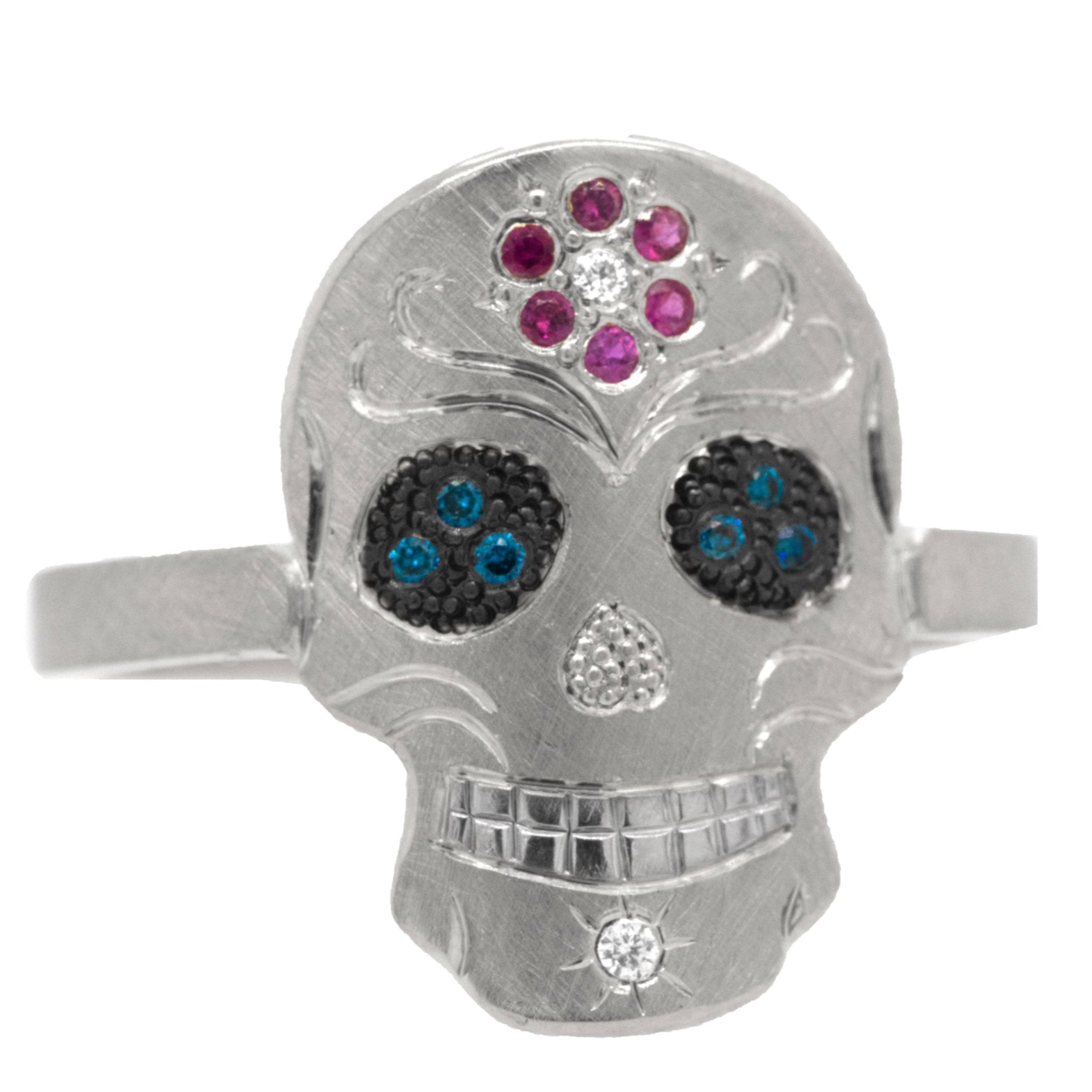 Silver skull-shaped ring with colored gemstones on a white background