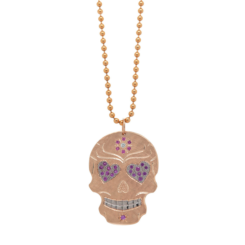 Vibrant colorful Julez Bryant original Ghostrider Collection gemstone encrusted sugar skull extra large pendant. 14k solid rose gold mixed diamond and sapphires. Fine detail engraving highlights features. Rhodium brightened eyes and teeth with pink sapphire pave set heart gemstone eyes. pink sapphire flower with white diamond 14 k solid rose gold . Milgrain details. Shown on 2.0mm ball chain.
