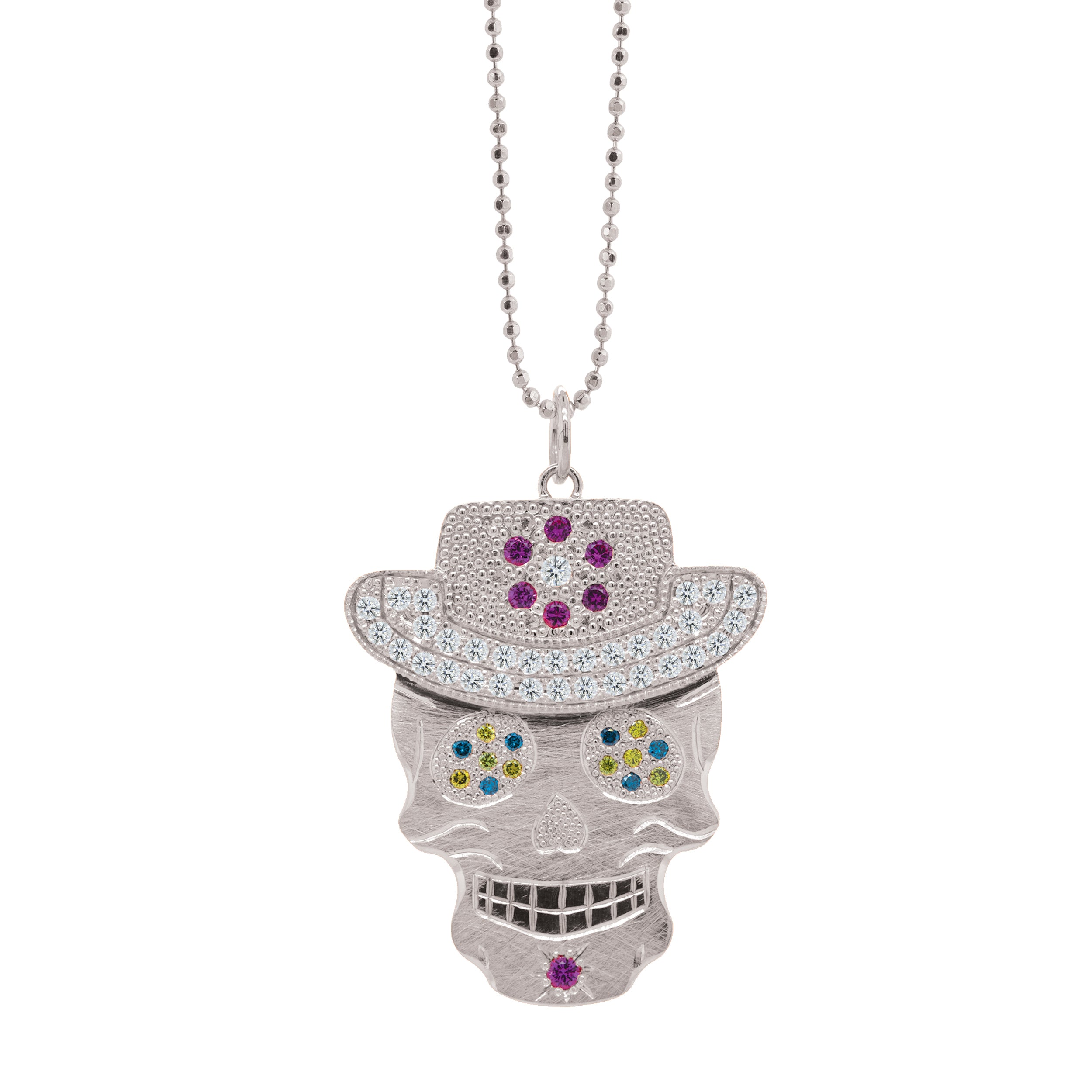 Cool toned with colorful accents this Julez Bryant original Ghostrider Collection Vaquero gemstone encrusted sugar skull wearing cowboy hat in white gold  rhodium darkened teeth. Extra large pendant in 14k solid white gold mixed diamond sapphires and Tzavorite. Fine detail engraving highlights features. Hat of flower clustered jewels in mixed colors. Eyes with green Tzavorite and blue sapphire pave set gemstone eyes. Large pink sapphire  and diamond Flower pave set detail on hat.  Shown on 2.0mm ball chain.