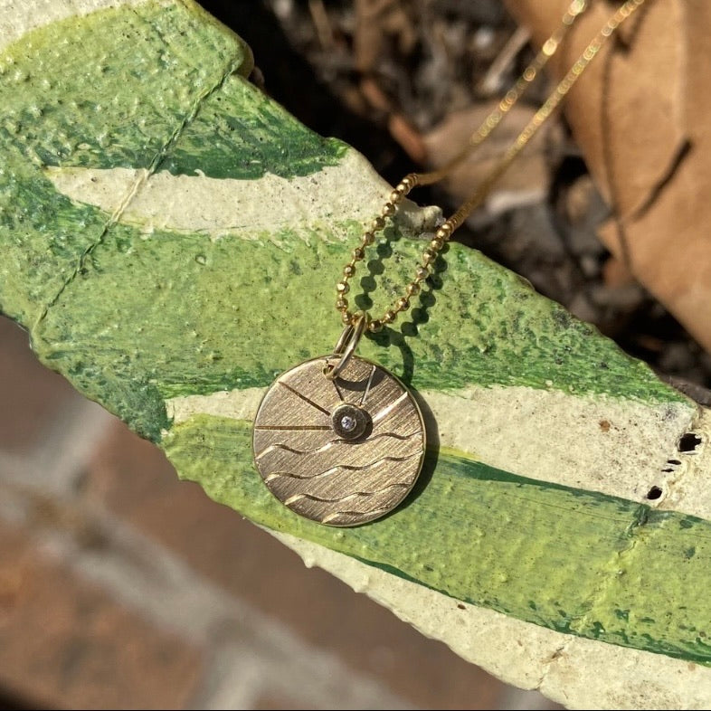 14k gold GOOS charm outside in sunshine